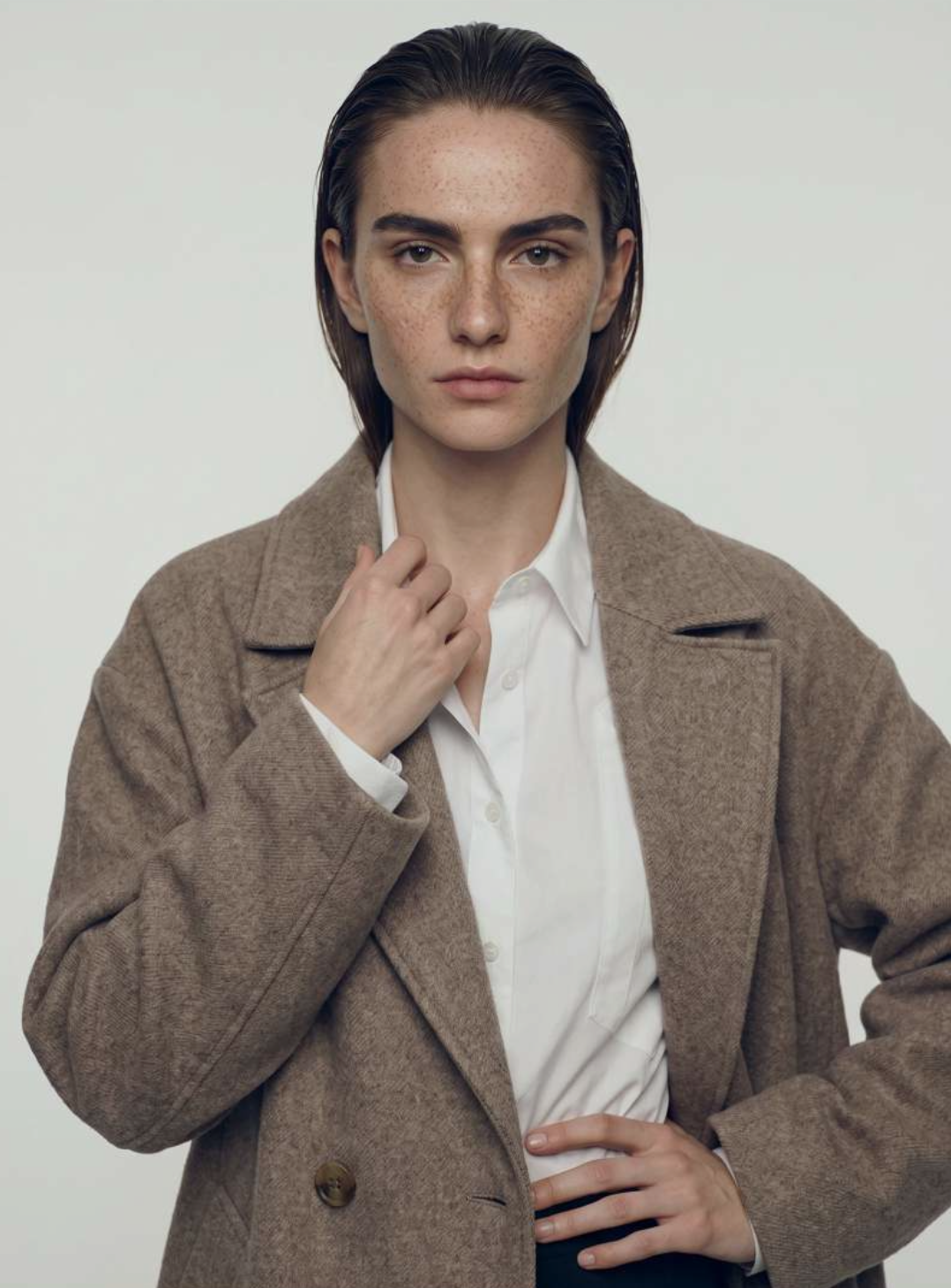 Taupe wool coat worn over a crisp white shirt.