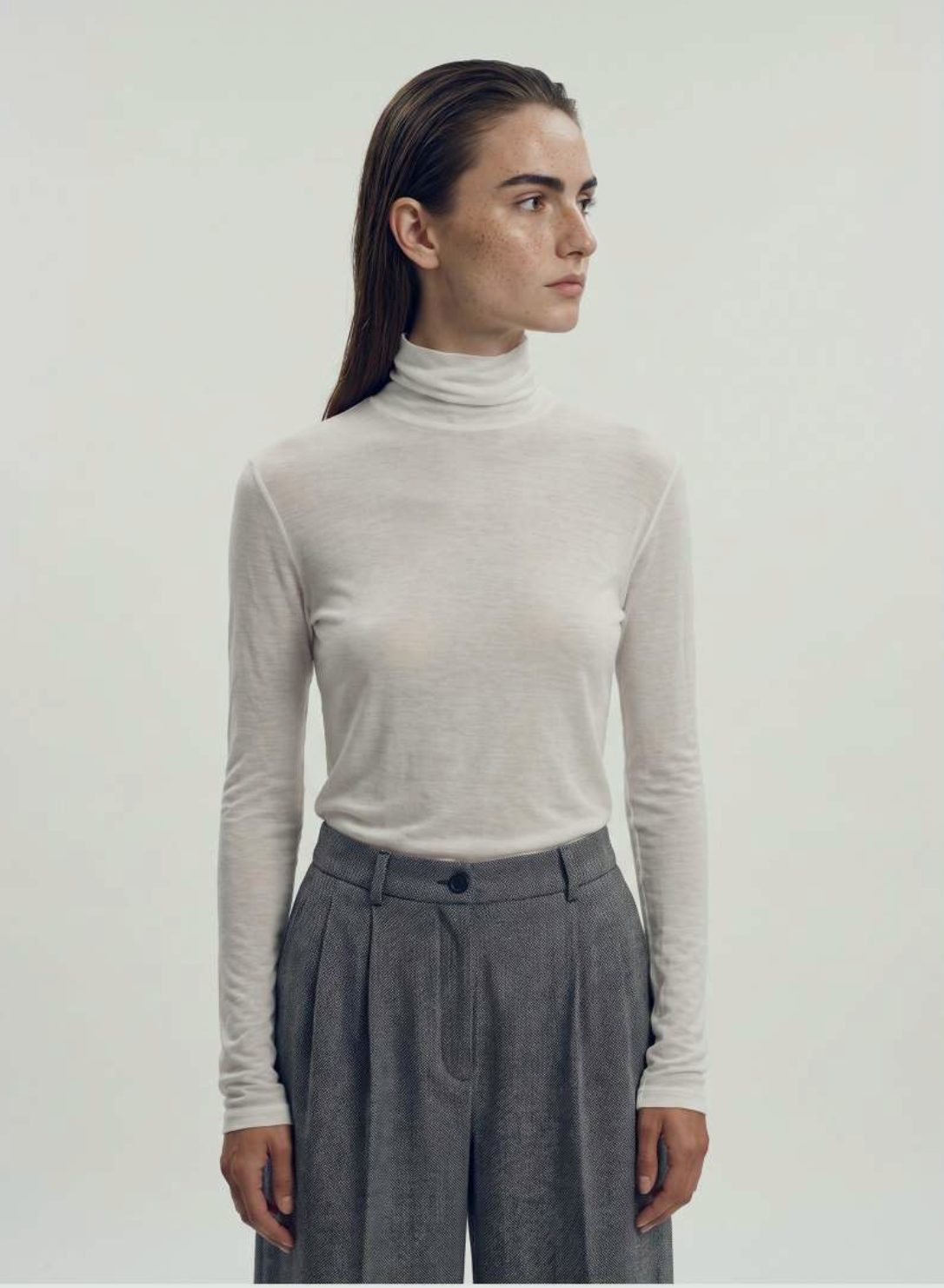 Fine ivory wool turtleneck with pleated grey wide-leg trousers.