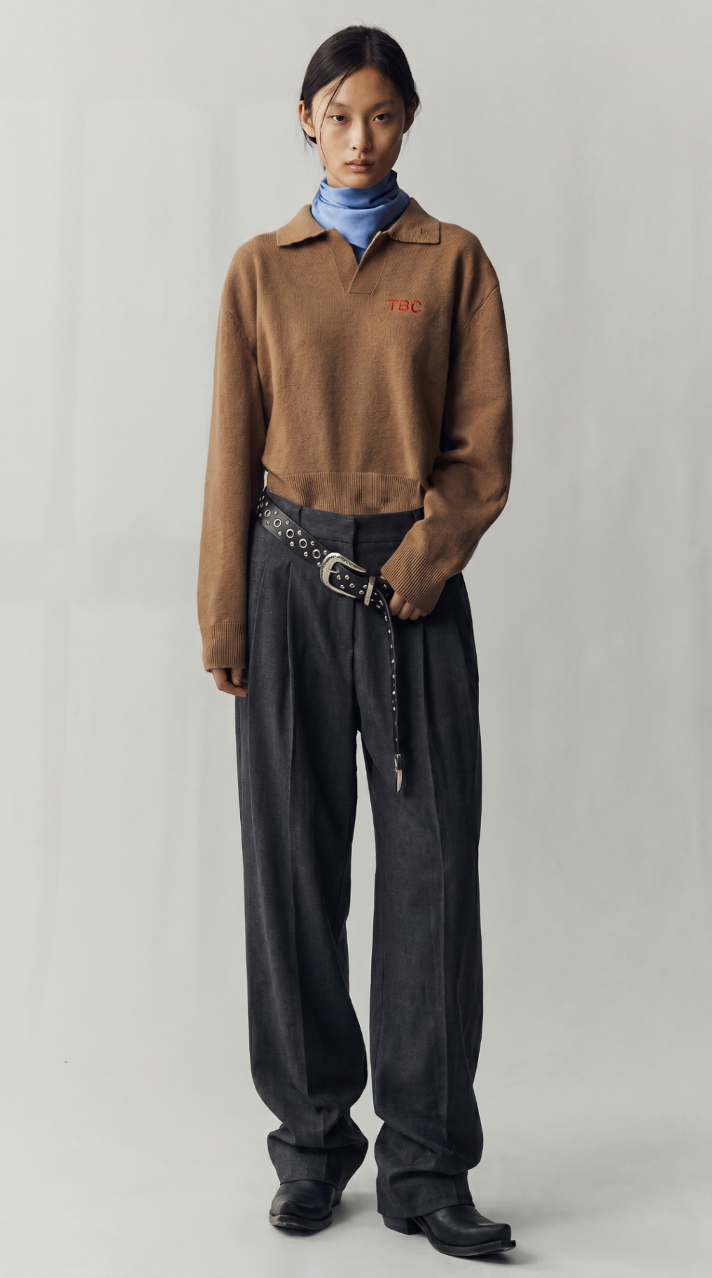 Look 02 — camel knit polo over a powder-blue turtleneck with relaxed charcoal trousers.