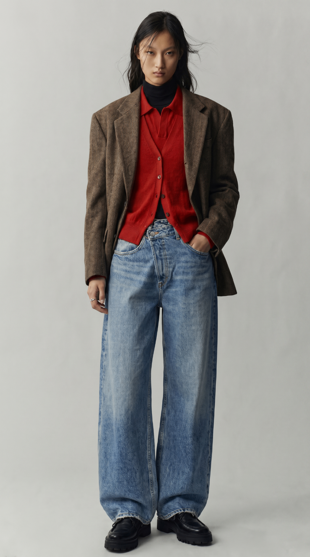 Look 04 — brown herringbone blazer layered over red knitwear and wide pale denim.