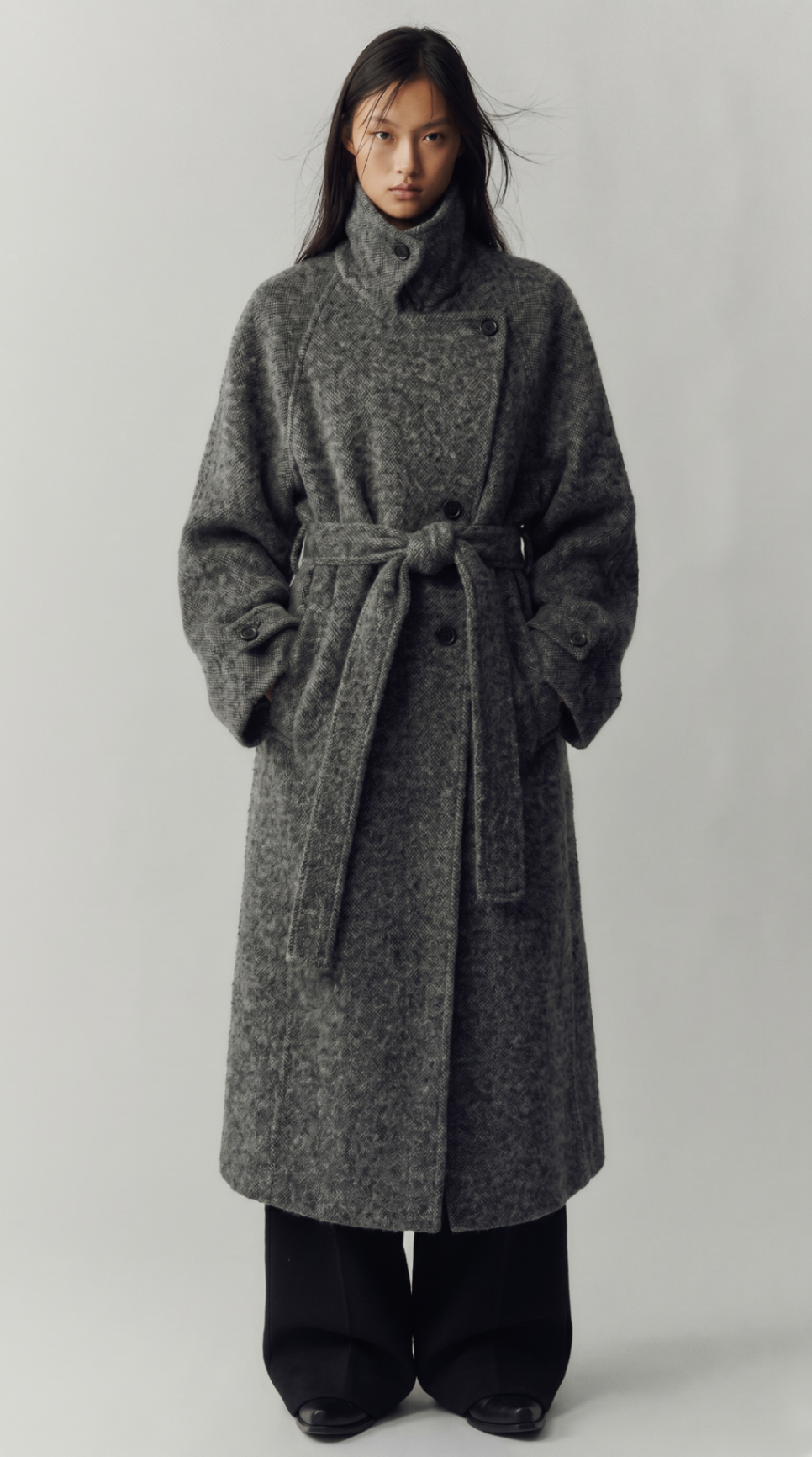 Look 09 — belted grey textured overcoat with a high collar over wide black trousers.