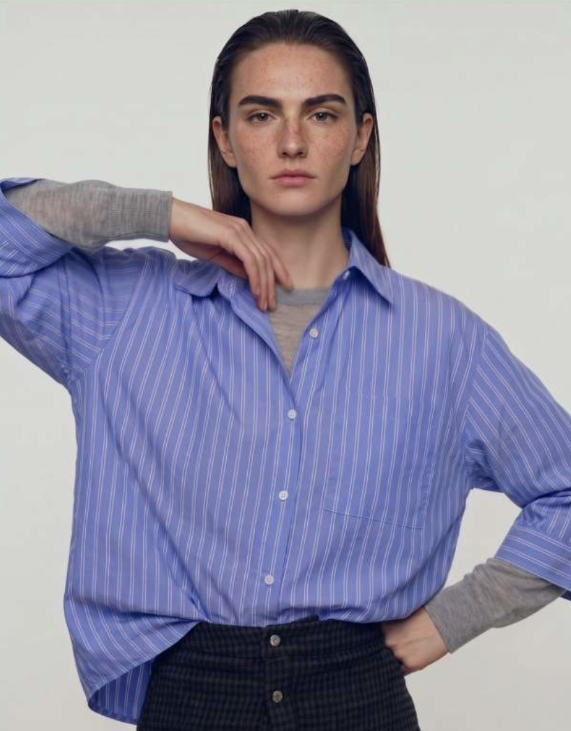 Oversized blue striped shirt layered over a grey knit with a dark checked skirt.